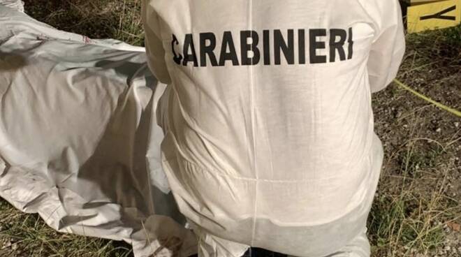 Un carabiniere nel corso dei rilievi vicino al cadavere coperto con un telo